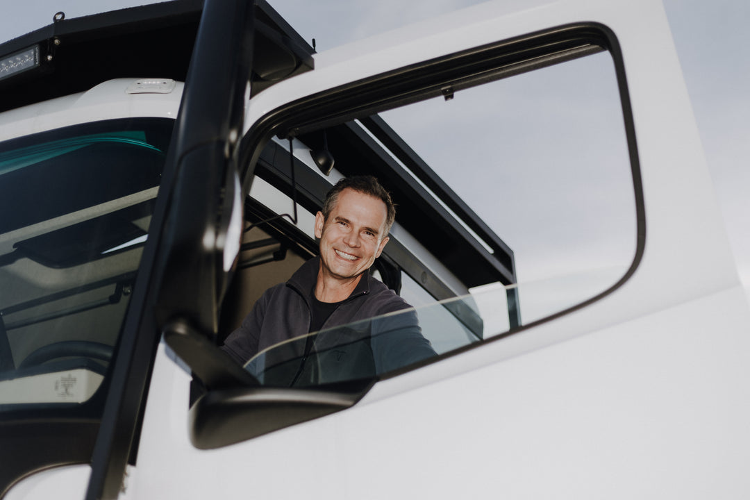 Ein freundlich lächelnder Mann im Führerhaus eines Expeditionsmobils